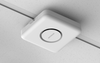 Netgear WBE758 Tri-Band WiFi 7 wireless access point mounted on ceiling with shadowed background.